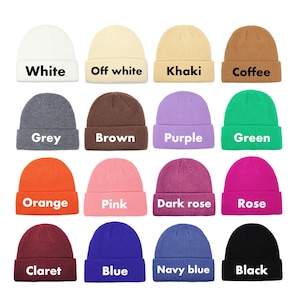 May include: A collection of colorful knit beanies in various shades, including white, grey, orange, and black. Each beanie has a folded cuff and a label with its color name. The image displays a range of colors, from neutral tones to vibrant hues.