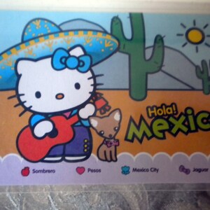 Könnte beinhalten: Eine Hello Kitty-Karte mit mexikanischem Thema. Hello Kitty trägt einen Sombrero und spielt eine rote Gitarre. Ein kleiner Hund ist neben ihr. Die Worte "Hola Mexico" stehen auf der Karte.