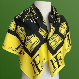 Könnte beinhalten: Ein quadratisches Tuch in Schwarz und Gelb mit aufgedruckten Grafiken von Pariser Straßenschildern, dem Eiffelturm sowie dem Text Paris, France, Avenue des Champs Elysees, Rue Montmartre und Chateau de Versailles.