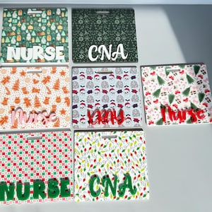 May include: A selection of Christmas-themed badge holders. Designs include gingerbread men, Christmas trees, and festive patterns. Each badge holder has a lanyard cutout and the words "Nurse" or "CNA" in various colours.