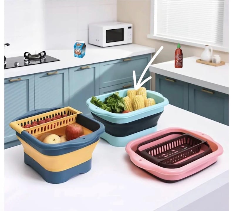May include: Collapsible kitchen containers in blue, yellow, and pink. One container holds corn and lettuce, another has apples and tomatoes, and the third is empty. A microwave and stove are in the background.