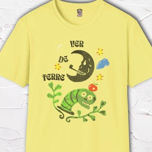 May include: Yellow t-shirt with a whimsical graphic featuring a smoking crescent moon, a green worm, and the text "VER DE TERRE". The design includes stars, a cloud, and an apple. The shirt is part of a collection of tees and sweatshirts, sizes S-3XL.