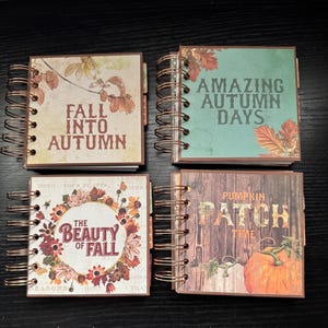 May include: Four small, spiral-bound notebooks with autumn-themed covers. The covers feature text like "Fall Into Autumn," "Amazing Autumn Days," "The Beauty of Fall," and "Pumpkin Patch Time." Each notebook has a different design with fall colors.