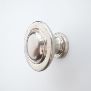 Könnte beinhalten: Silberfarbener Schrankknauf mit ovaler Front und abgerundeter Basis. Der Knauf ist aus Metall und hat eine glatte, reflektierende Oberfläche. Die Hardware ist für den Einsatz an Schubladen oder Schränken konzipiert.