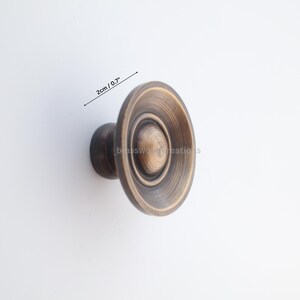 Puede incluir: Tirador de armario de bronce antiguo con dise&ntilde;o circular. El pomo mide 2 cm de di&aacute;metro. El herraje tiene un acabado en bronce oscuro y es adecuado para cajones y armarios.