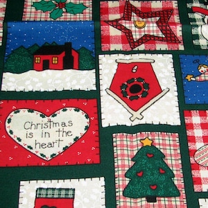 May include: A dark green fabric featuring a patchwork pattern of various holiday-themed squares. Designs include a snowman, a Christmas tree, a red house, a stocking, and hearts with the text "Christmas is in the heart" printed on them.