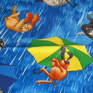 May include: A blue background with white rain streaks. A yellow, green, and white umbrella with a brown dog holding onto it. A brown dog with a white spot on its chest is falling from the sky. A black cat with white spots is falling from the sky. A black cat with white spots is falling from the sky.