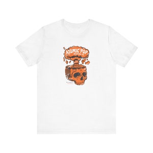 May include: White t-shirt featuring an orange graphic of a skull with an exploding brain. The graphic reads "Atomic Pop Trading Co."