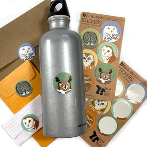 May include: A silver water bottle with a sticker of an owl on it. The sticker is part of a set of stickers featuring different types of owls. The stickers are waterproof and come in a sheet of 8. The text on the sticker sheet reads "Bird vs Bird Stickers".