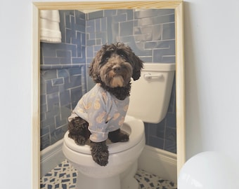 Op de afbeelding: Een ingelijste foto van een zwarte hond die een blauw-wit gebloemd shirt draagt ​​en op een wit toilet zit in een badkamer met blauwe tegels.