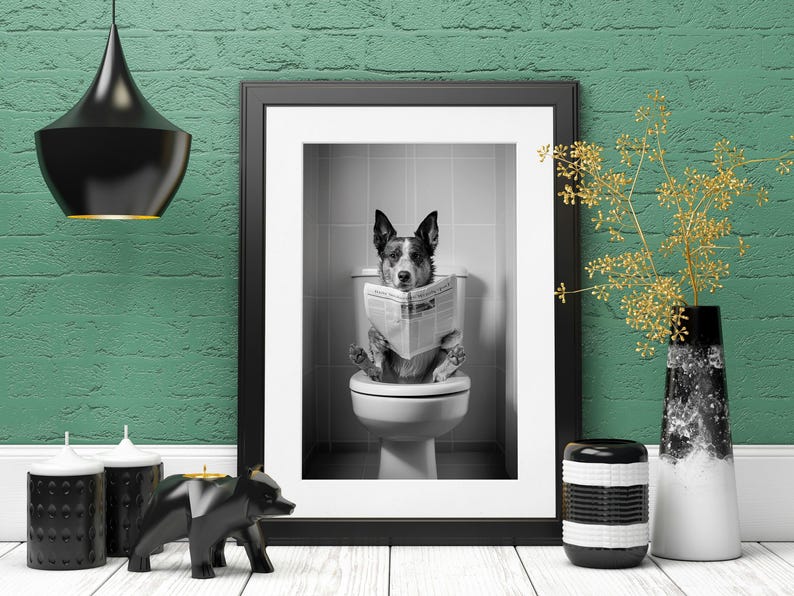 May include: A black and white photo of a dog sitting on a toilet and reading a newspaper. The photo is framed in a black frame and hanging on a green brick wall.