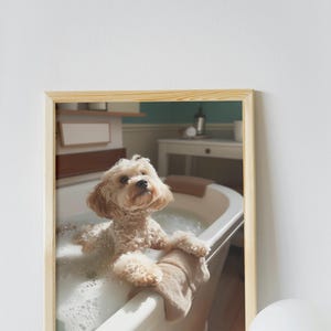 May include: A small, light brown dog sits in a white bathtub filled with bubbles. The dog is looking up at the camera with a curious expression. The bathroom is decorated in a vintage style with a light blue wall and a white vanity.