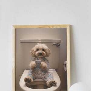 May include: A framed photograph of a dog wearing pajamas sitting on a toilet and looking at a cell phone.