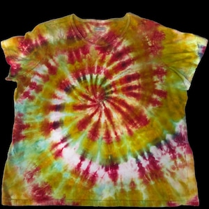 May include: A short-sleeved, round-neck t-shirt with a spiral tie-dye pattern. The shirt features a vibrant color scheme of red, yellow, green, and white, creating a psychedelic effect. The tie-dye design radiates from the center of the shirt.