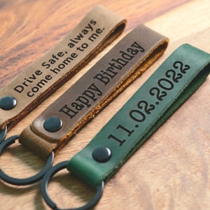 May include: Three leather keychains with different engraved messages. The first keychain is brown and says "Drive Safe, always come home to me." The second keychain is brown and says "Happy Birthday." The third keychain is green and says "11.02.2022."