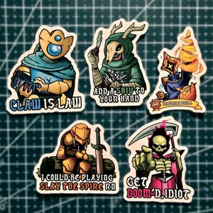 May include: Five die-cut vinyl stickers featuring fantasy characters and game-inspired text. Designs include a blue-clad figure with 'CLAW IS LAW', a hooded skull figure with 'ADD A SHIV TO YOUR HAND', a drill with 'HEAVENLY DRILL', a knight with 'I COULD BE PLAYING SLAY THE SPIRE RN', and a skeleton with 'GET DOOM'D, IDIOT'.