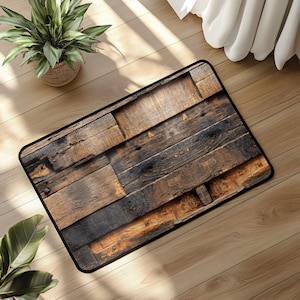 Może przedstawiać: Prostokątna wycieraczka z wzorem zniszczonych desek drewnianych. Mata ma czarną obwódkę i wzór w różnych odcieniach brązu i czerni, przypominający odzyskane drewno. Mata jest umieszczona na jasnej drewnianej podłodze.