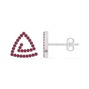 May include: A pair of silver stud earrings. Each earring features a triangular design with a spiral detail, outlined and filled with small, round, dark red gemstones. The earrings are displayed against a white background.