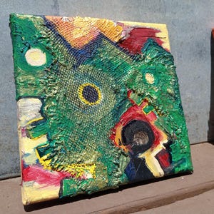 May include: Abstract painting on canvas with a textured surface. The artwork features a vibrant mix of colors, including green, yellow, red, and black. The composition includes circular and geometric shapes, creating a unique visual texture. The painting is mounted on a wooden frame.