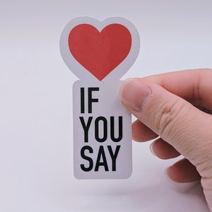 May include: A die-cut sticker featuring a red heart shape at the top and a white rectangular base below. The text IF YOU SAY is printed in bold black sans-serif capital letters on the white section of the sticker against a plain background.