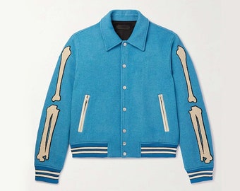 May include: A blue varsity jacket with white and blue stripes on the cuffs and hem. The sleeves feature a skeleton bone design in cream.
