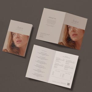 以下が含まれることがあります： Aura Aestheticsのパンフレットセット。パンフレットは、Aura Aestheticsのロゴと女性の顔が描かれた薄いベージュ色です。パンフレットは、テキストと提供されるサービスを表示するために開かれています。パンフレットは濃い灰色の表面にあります。