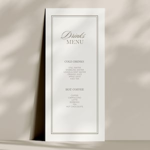 May include: A tall, rectangular white drinks menu card featuring a thin black double-line border. The text reads Drinks MENU, COLD DRINKS including still water, sparkling water, lemon & mint water, orange juice, apple juice, iced tea, and HOT COFFEE.