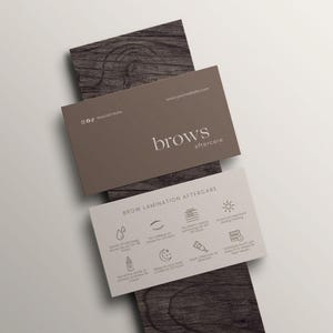 May include: Two business cards with the text "brows aftercare" and "Brow Lamination Aftercare" on a wooden surface. The top card is brown with social media icons and a website address. The bottom card is white with aftercare instructions.
