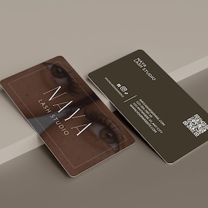May include: Two rectangular business cards for Naya Lash Studio. One card features a close-up image of an eye with long lashes and the text NAYA LASH STUDIO. The other dark brown card displays the studio name, social media icons, contact info, and a QR code.