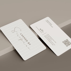 May include: Two rectangular business cards with rounded corners. One card features a lined pattern and the text 'LASHED BY Serapine'. The other card displays 'SERAPINE LASH STUDIO', social media icons, contact information, and a QR code.