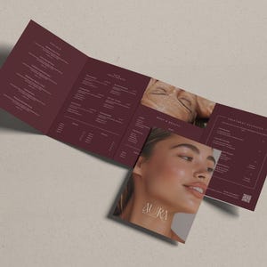 Puede incluir: Un folleto tríptico en color burdeos oscuro con texto blanco que enumera servicios de spa, incluyendo faciales, tratamientos de piel y paquetes corporales. La portada muestra una foto de un rostro y el texto Aura Aesthetics con un código QR.