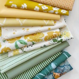 May include: A stack of fabric swatches in various shades of yellow and green. The fabrics feature floral patterns, stripes, and geometric designs.