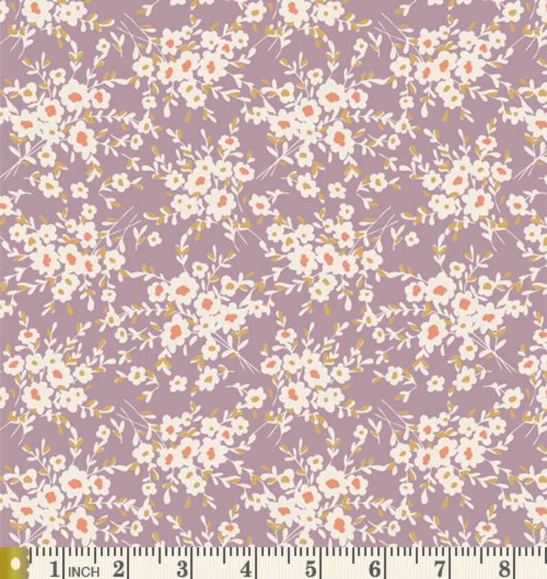 May include: A purple fabric with a white and orange floral pattern. The fabric is shown with a ruler for scale.
