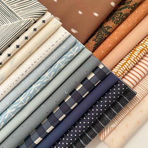 May include: A collection of folded fabric swatches arranged in a diagonal stack. The patterns include black and white stripes, small crosses, blue floral motifs, navy blue gingham, white polka dots on dark blue, and various solid earth tones.
