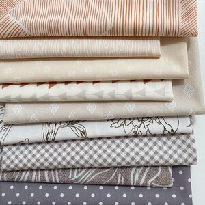 May include: A stack of folded fabric pieces featuring various patterns including vertical stripes, wood grain, small floral motifs, geometric triangles, diamonds, floral line art, a small checkered pattern, organic leaf shapes, and white polka dots.