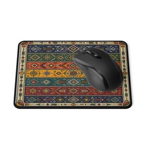 May include: A rectangular mousepad with a colorful, patterned design resembling a traditional rug. The design features a mix of red, blue, yellow, and green geometric shapes. A black wireless mouse rests on the pad.