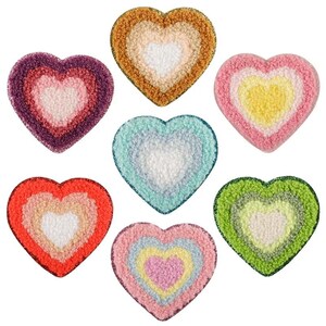 May include: Seven plush heart-shaped cushions in various colors, each with a smaller heart in the center. The colors include pink, orange, green, blue, yellow, and brown.