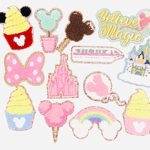 May include: A set of 13 iron-on patches featuring various Disney-themed designs, including Mickey Mouse, Minnie Mouse, Cinderella's Castle, a rainbow, and a castle with the text "Believe in Magic".