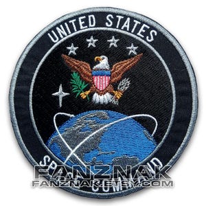 May include: Circular embroidered patch with the words "UNITED STATES" and stars above an eagle emblem. The patch has a black background with a blue globe and white accents. The text "SPACE COMMAND" and "FANZNAK.ETSY.COM" are also visible on the patch.