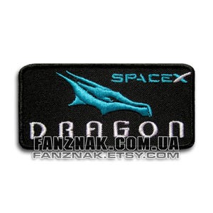 May include: Black rectangular patch with a turquoise dragon design and the word "SPACEX". The word "DRAGON" is embroidered in white, along with "FANZNAK.COM.UA" and "FANZNAK.ETSY.COM".