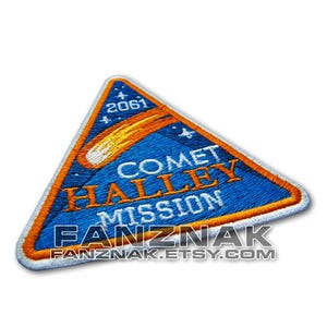 May include: A blue and orange triangular embroidered patch with the text "Comet Halley Mission" and the year "2061".
