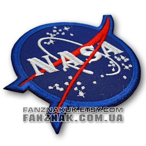 May include: A circular embroidered patch featuring a deep blue background with white stars and the white NASA logo text. A bold red swoosh cuts diagonally across the centre. The text FANZNAKUK.ETSY.COM and FANZNAK.COM.UA is printed below the patch.