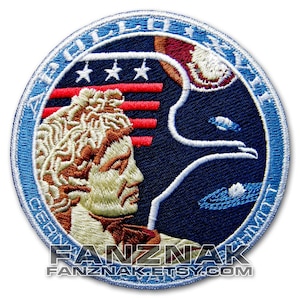 May include: A blue and white embroidered patch featuring a profile of a man's face, a bald eagle, and the text "Apollo-Soyuz Test Project".