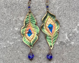 Hand painted peacock feather leather earrings in shimmering green. Asymmetrical dangle earrings w/ cobalt glass drops, rustic boho jewelry.