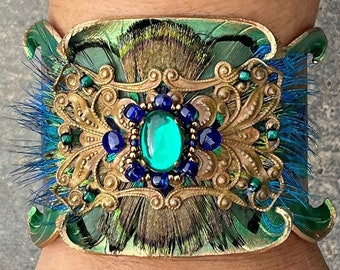 Tooled leather cuff bracelet with colorful peacock feather motif. Whimsical mixed media leather jewelry with vintage brass filigree.