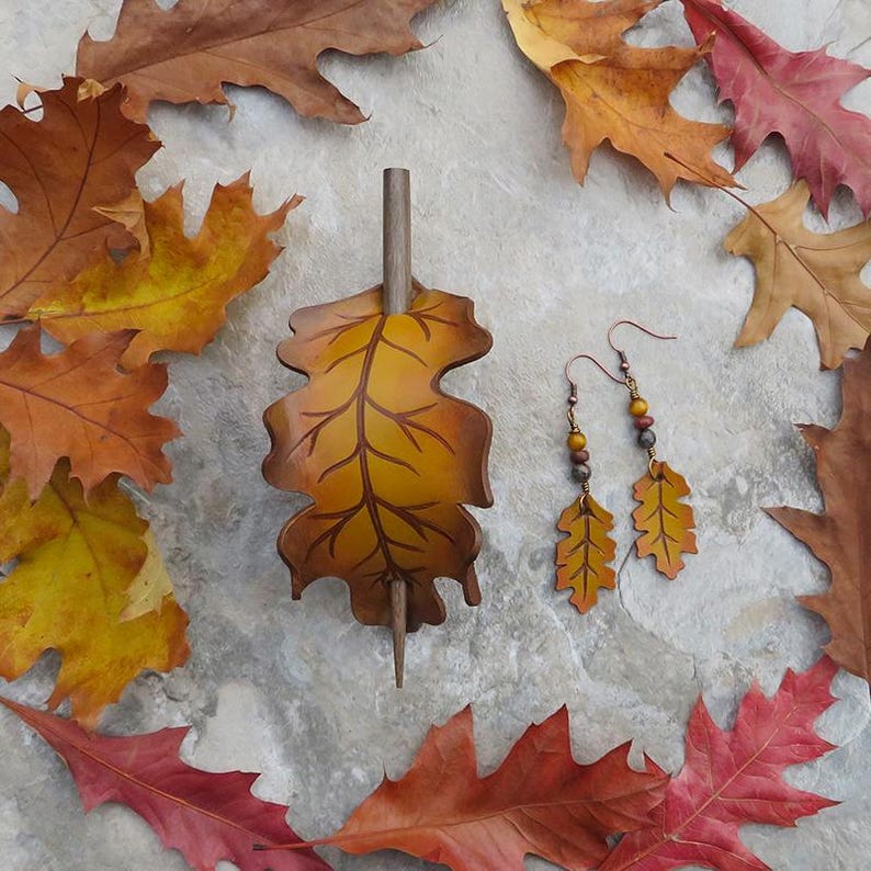 Peut inclure: Un pic &agrave; cheveux et des boucles d'oreilles assorties faits &agrave; la main, en forme de feuilles d'automne. Le pic &agrave; cheveux est une grande feuille stylis&eacute;e avec une cheville en bois. Les boucles d'oreilles pr&eacute;sentent de petits pendentifs en forme de feuilles avec des perles. Couleurs : jaune, orange et marron.