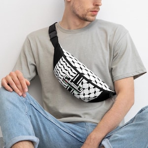 Puede incluir: Riñonera en blanco y negro con un patrón geométrico. La riñonera tiene una correa y hebilla negras. La riñonera tiene texto en el centro.