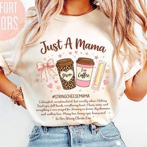May include: Cream-colored t-shirt with the text "Just A Mama" and illustrations of coffee cups, a bow, and a string cheese stick. The shirt also features the hashtag #STRINGCHEESEMAMA and a poem. The words "COMFORT COLORS" are in a pink circle.