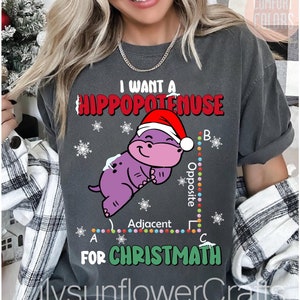 May include: A grey t-shirt featuring a purple cartoon hippopotamus wearing a Santa hat. The hippopotamus is on a graph with the text "I want a hippopotamus for Christmath".