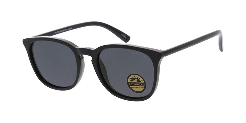 Pu&ograve; includere: Occhiali da sole neri con lenti polarizzate grigio scuro. Gli occhiali hanno una montatura quadrata e un adesivo con la scritta "Polarized" e "UV400 Protection". Le aste sono sottili e dritte.